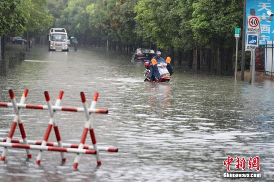 资料图：6月12日，贵阳市民骑电动车在积水路段行驶。记者 贺俊怡 摄