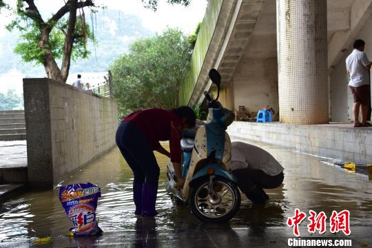 一位市民在被洪水淹没的道路上洗车。　王以照 摄